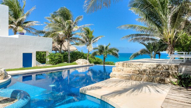 A swimming pool with a clear blue water, surrounded by palm trees and a view of the ocean. - Luxury Ocean Front Villa,  6BR (12 pax) Breakfast includes + infinity pool (Isla Mujeres)