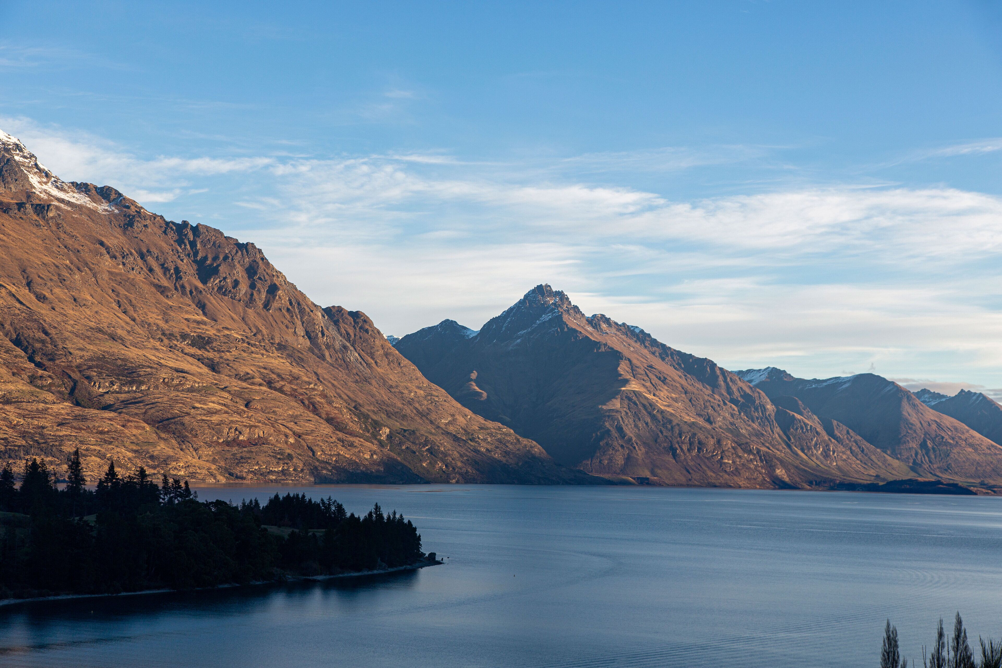 A mountainous landscape with a calm lake and a small island with trees.