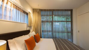 Hotellihuone, jossa on suuri sänky, ikkuna, jossa on verhot, ja näkymä vehreään maisemaan.