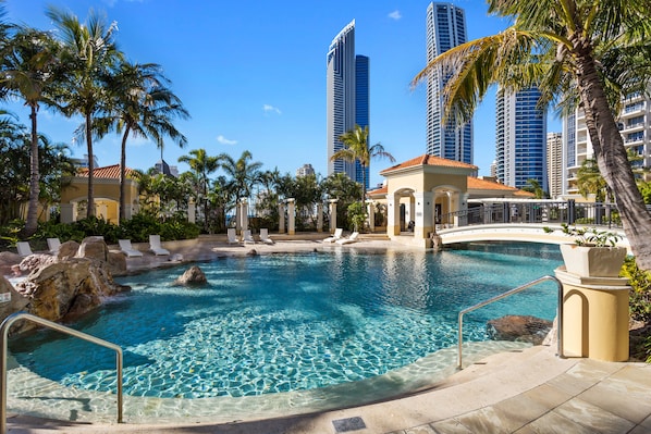 A pool area with clear water, palm trees, and high-rise buildings in the background. - Chevron Renaissance Ocean View (Surfers Paradise)