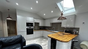 Una cocina moderna con una isla de madera, electrodomésticos integrados y un tragaluz.