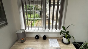 Un espacio de trabajo con un escritorio, dos jarrones negros, una lámpara, una silla y una planta en maceta.