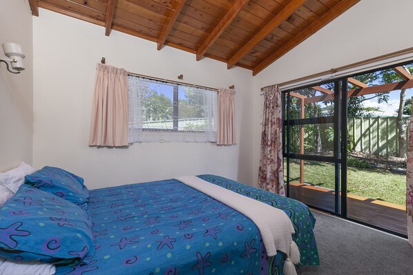 A bedroom with a large bed, a window with curtains, and a view of the outdoors.