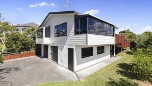 Ein modernes, zweistöckiges Haus mit flachem Dach, großen Fenstern und einer Satellitenschüssel.