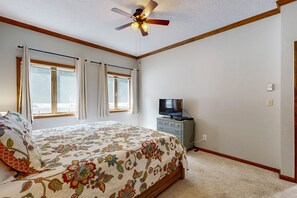 Relax in this serene bedroom with a large bed, ceiling fan, and television.