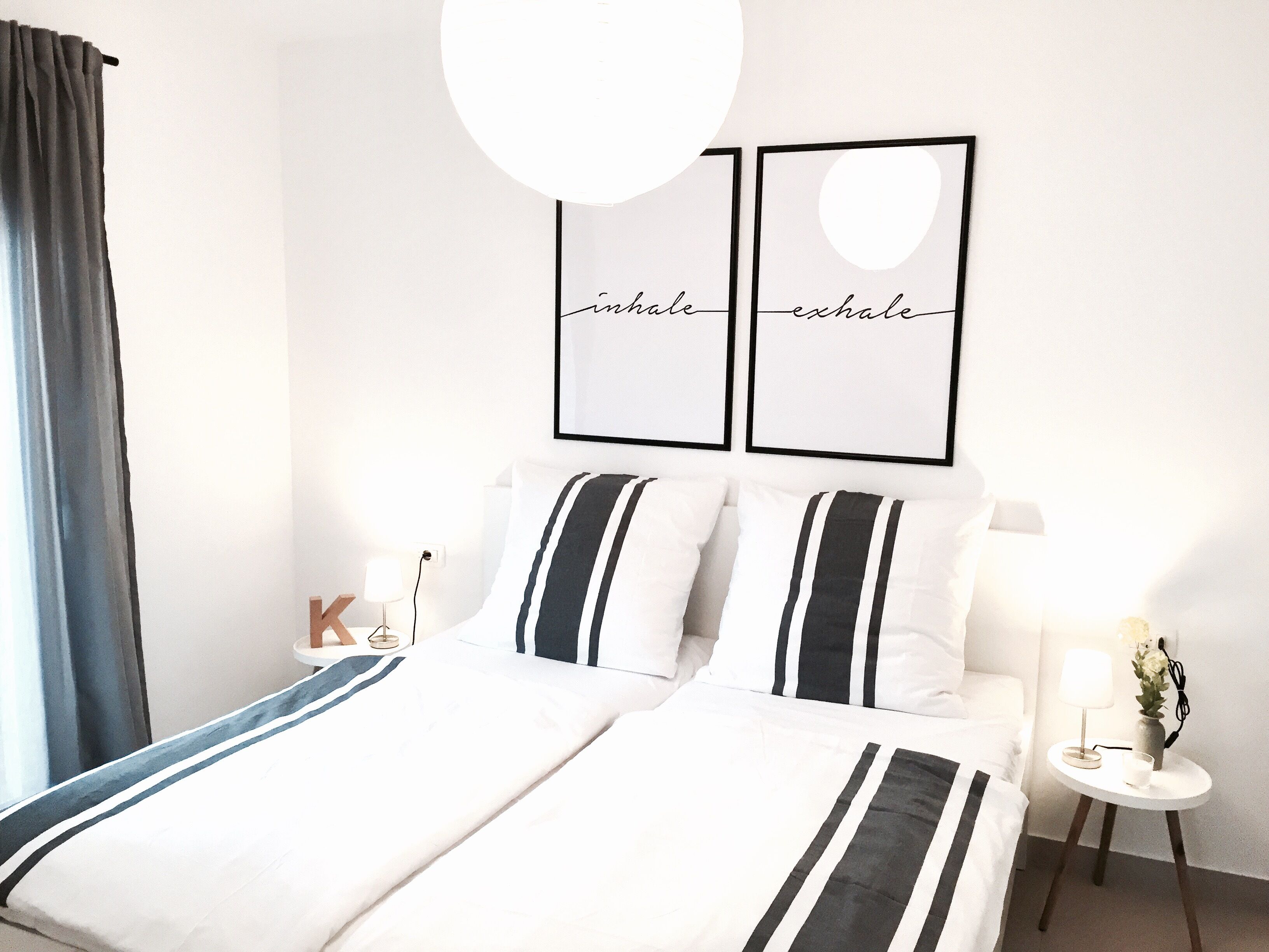 Una camera d'albergo con un letto, un comodino con una lampada e due citazioni motivazionali incorniciate appese al muro.