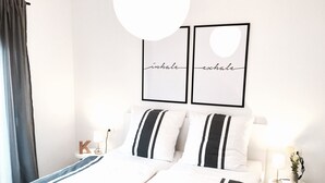 Ett välordnat hotellrum med en säng, ett sängbord med en lampa och två inramade ord på väggen.