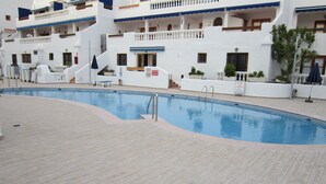 Un espace autour d’une piscine doté d’une terrasse en bois, de chaises longues et d’un panneau indiquant qu’il est interdit de se baigner.