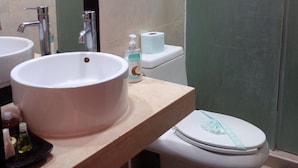 A bathroom with a large white sink, a mirror, a toilet with a decorative ribbon, and a towel rack. - Aldea Thai jr suite. Or Studio By OceanFront  for upto 4 pax  (Playa del Carmen)