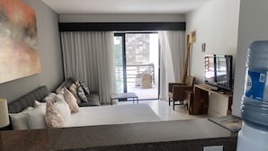 A modern hotel room with a large bed, a sofa, a TV, and a water dispenser. - Aldea Thai jr suite. Or Studio By OceanFront  for upto 4 pax  (Playa del Carmen)