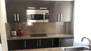 A kitchen with granite countertops, stainless steel appliances, and dark cabinetry. - Aldea Thai jr suite. Or Studio By OceanFront  for upto 4 pax  (Playa del Carmen)