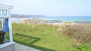 A coastal view with a grassy area, a building with a window, and a clear sky. - C35 Le Grace, Riviere Towans (Hayle)