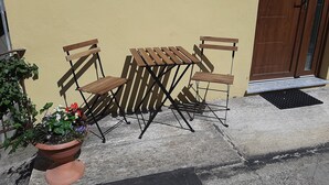 A patio with a wooden table and two chairs, a potted plant, and a door. - La CasaLina - tourist rental (Omegna)
