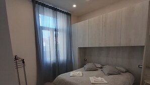 A bedroom with a bed, a headboard, a window with curtains, and a ceiling light. - La CasaLina - tourist rental (Omegna)