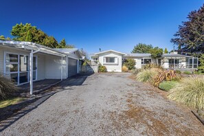 A row of mobile homes with a gravel driveway and surrounding vegetation.