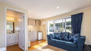 A modern living room with a sofa, a dining area, and a kitchen.