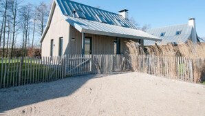 A modern building with a sloped metal roof, a gravel driveway, and a wooden fence.