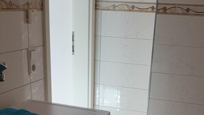 Een kleine, moderne wasruimte met een voorlader wasmachine, een handdoekhouder en een deur naar een andere ruimte.