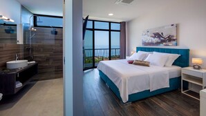Quarto moderno com uma cama grande, mesa de cabeceira e banheiro com chuveiro e pia.