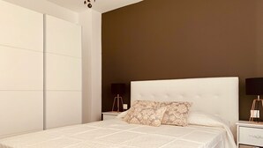 A bedroom with a large bed, a bedside table, a nightstand, and a wardrobe. - A&F Comfort Modern House (Santa Lucía de Tirajana)