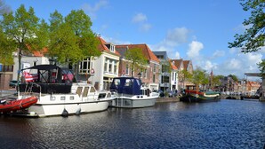 A canal with boats docked along the side, surrounded by traditional European-style buildings. - BERGEN: 'Boschlust', beautiful apartments in country house style and close to the beach! (Bergen)