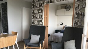 A modern living room with two grey armchairs, a wooden dining table, and a small black side table with a tray. - New apartment with terrace view and sea access 2 people all comfort / bicycles (Saint-Jean-de-la-Rivière)