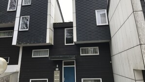 Un immeuble à plusieurs étages, doté d’une façade sombre, de nombreuses fenêtres et d’une porte bleue.