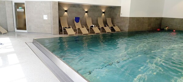 Piscina con sillas de descanso y una puerta con la inscripción "AUSGANG".