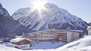 A hotel with multiple balconies, a ski lift, and a mountain backdrop. - Modern furnishings, balcony. wonderful mountain view summer - mountain railway ticket inc. (Mittelberg)