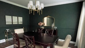 Comedor con una mesa de madera oscura, sillas a juego, una araña y un espejo grande.