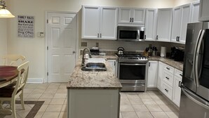 Una cocina moderna con armarios blancos, electrodomésticos de acero inoxidable y encimera de granito.