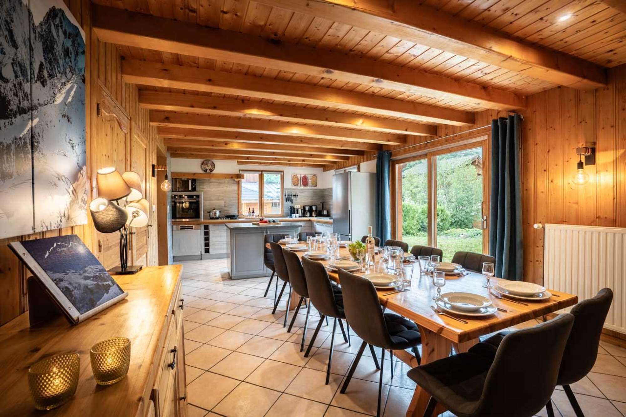 Un intérieur en bois comprenant un coin repas, une cuisine et de grandes fenêtres.