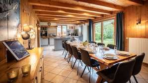 A wooden interior with a dining area, kitchen, and large windows. - Chalet Snow Paradise (Les Belleville)