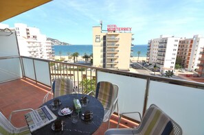 Un balcon avec une table, des chaises et un journal. On aperçoit au loin un hôtel qui s’appelle « HÔTEL MONTERREY ».