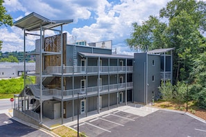 A multi-story building with balconies, a parking lot, and a stop sign.