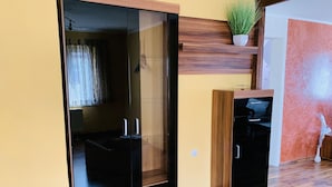 A room with a sliding glass door leading to a dark interior, a wooden cabinet with a plant on top, and a small statue on the floor. - "FeWo Tante Ju" with a view of the Bauhaus in Dessau-Roßlau (Dessau-Roßlau)