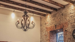 A dining area with a white table, chairs, and a chandelier. There is a painting on the wall and a TV mounted above the table. - Luxurious apartment in historic building  downtown Puebla SV311 -12 (PUEBLA)