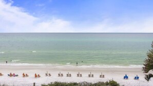 Ein Strand mit Liegestühlen und Sonnenschirmen, ein klarer Himmel und ruhiges Meer.