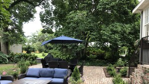 A patio area with a brick pathway, outdoor furniture, and lush greenery. - 1901 Historic Home's Guest Cottage with pool  (Lafayette)