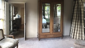 A room with a large wooden cabinet, a chair, and a view through a glass door. - 1901 Historic Home's Guest Cottage with pool  (Lafayette)