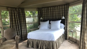 A bedroom with a large bed, a chair, and a nightstand with a lamp. - 1901 Historic Home's Guest Cottage with pool  (Lafayette)