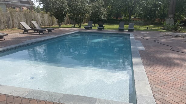 A rectangular swimming pool with a brick border and a paved deck. - 1901 Historic Home's Guest Cottage with pool  (Lafayette)