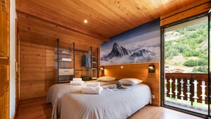 Une pièce en bois avec deux lits, une armoire et un tableau représentant une montagne.
