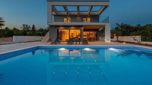 Una casa moderna de dos pisos con una piscina delantera.