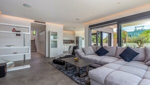 Una sala moderna con un sofá seccional gris, una mesa de centro y un aparador de vidrio.