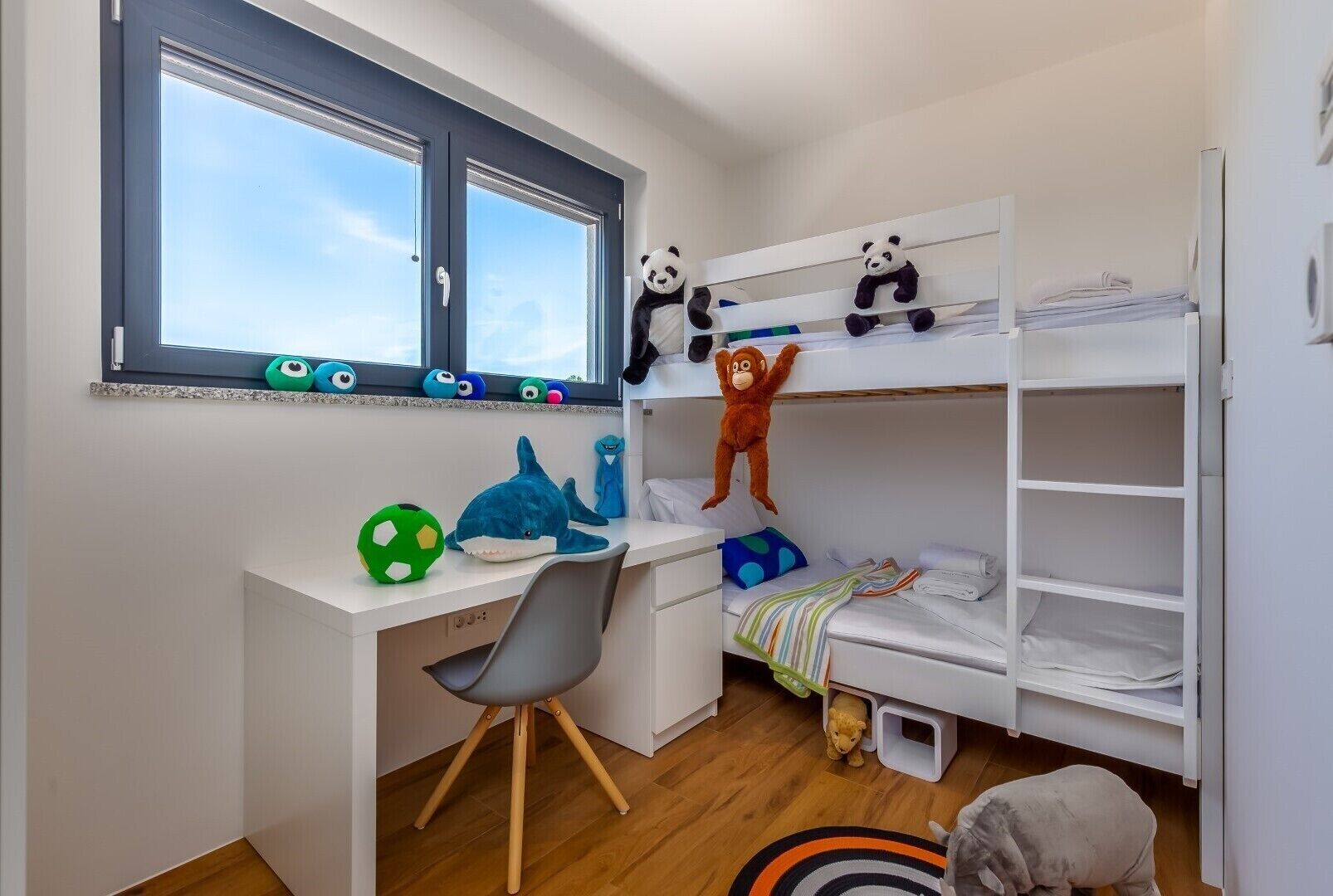 Une chambre d’enfant avec des lits superposés, un bureau et des jouets.