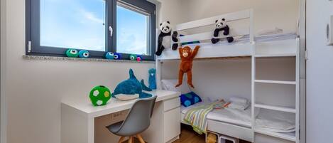 Une chambre d’enfant avec des lits superposés, un bureau et des jouets.