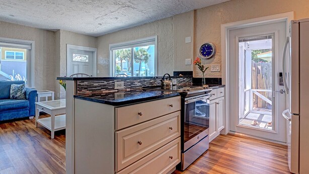 Una cocina con una isla central, muebles blancos y vistas al exterior.