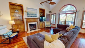 A spacious living room with a fireplace, wooden shelves, a large sofa, and a television.