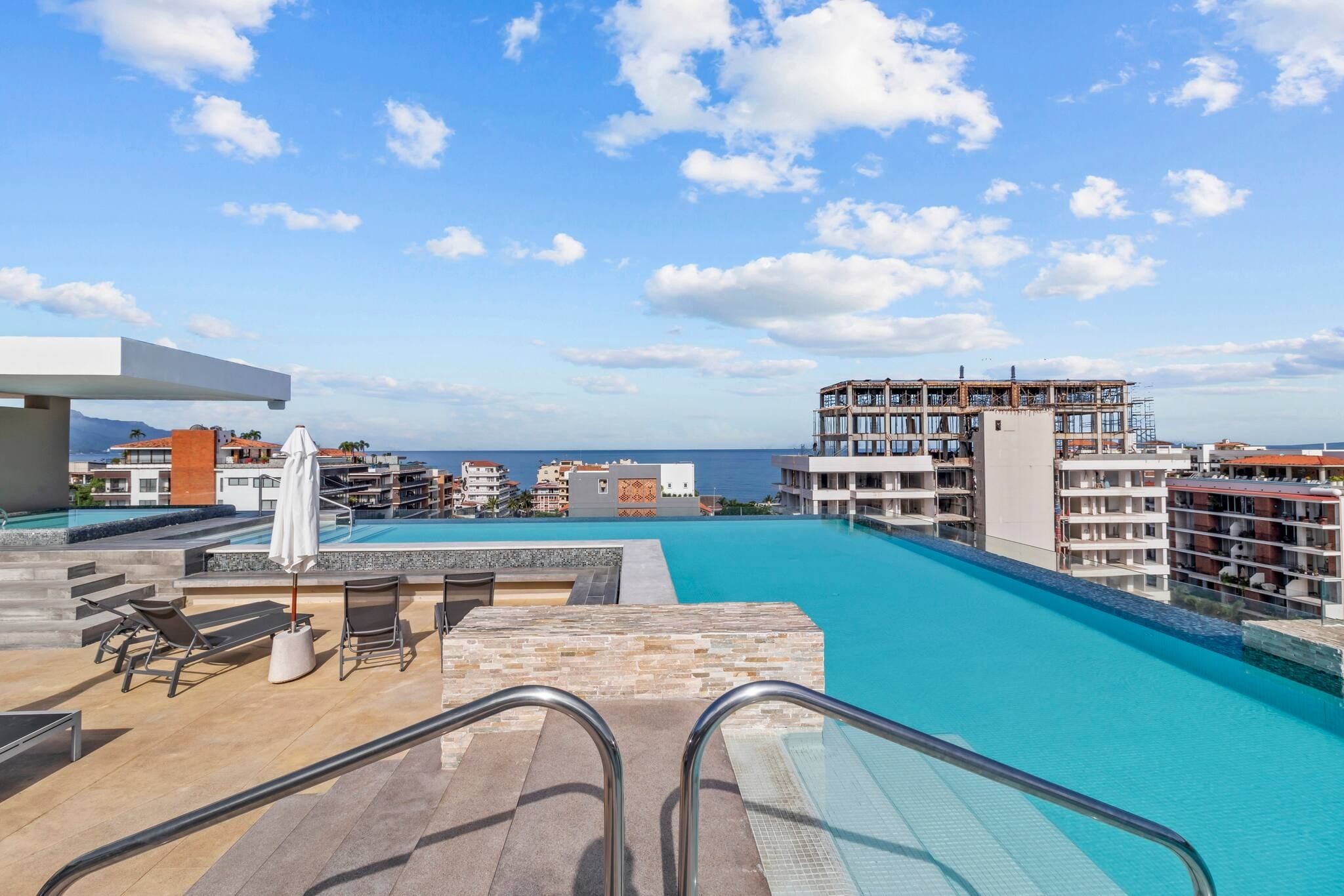 En resort-pool med krystalklart havudsyn og tilstødende bygninger.